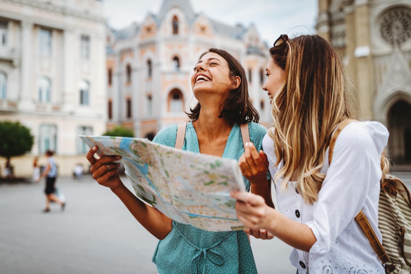 Two friends laughing over a paper map on a city street